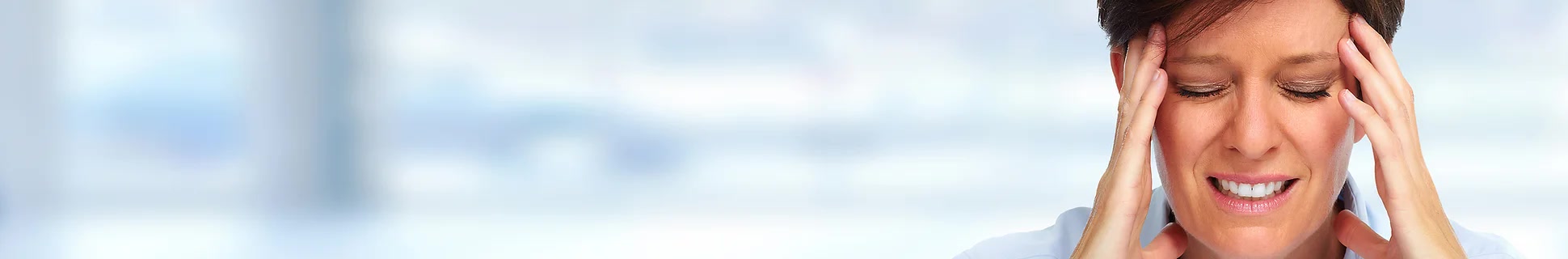 Woman holding her temples in pain from a migraine caused by nighttime teeth clenching